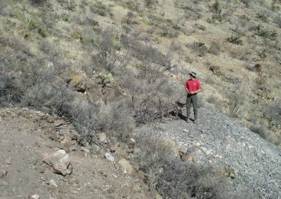 A man in a red shirt standing on a large mound of gravel