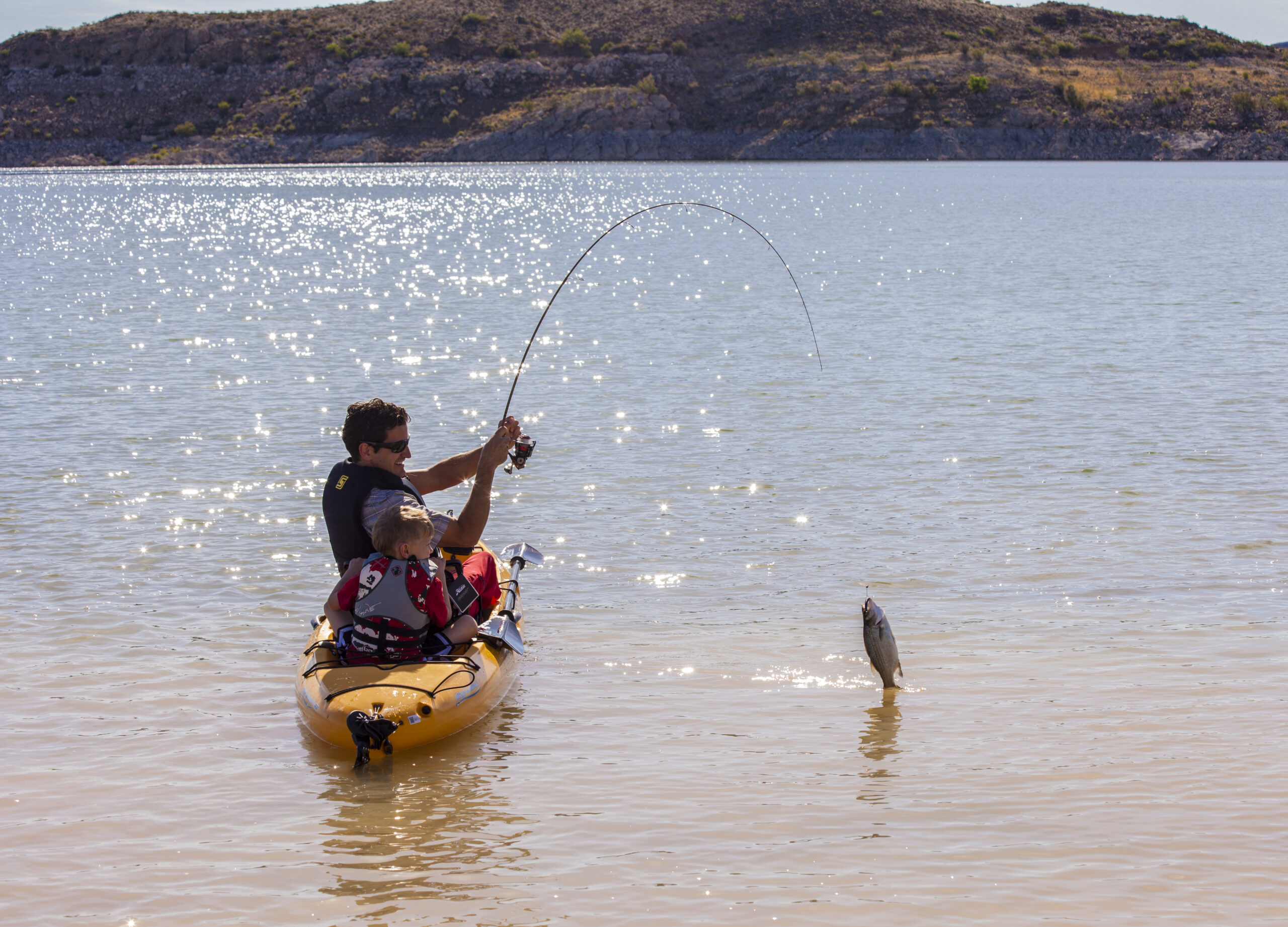Father and son catch a fish at Elephant Butte Lake State Park while kayaking.