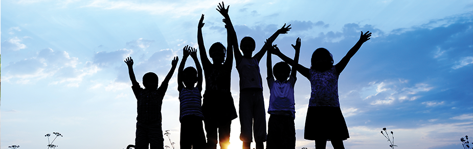 Silhouettes of children against sky, arms raised