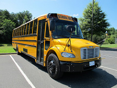 bus_000 Yellow school bus in parking space, green trees and blue sky